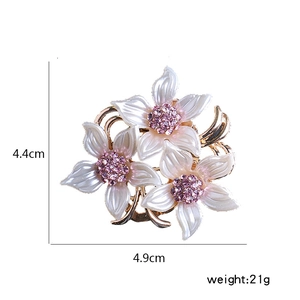 Détail d'une broche à fleurs avec cristaux roses et pétales dégradés pour foulard