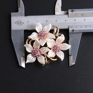 Vue détaillée d'une broche trois fleurs avec strass roses, pétales blancs et mesures précises
