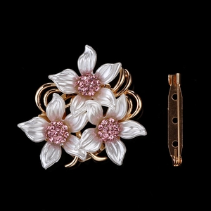 Détail macro d'une broche florale avec pétales nacrés blancs et strass roses