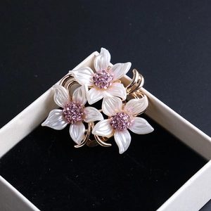 Élégante broche fleur dorée avec pétales de perles blanches et cristaux violets
