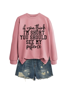 Detail of pink crewneck sweatshirt featuring black humor slogan print and denim shorts
