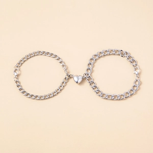 Macro detail of silver tone chain bracelets with magnetic heart charm and lobster clasp