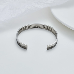 Dettaglio della citazione incisa e del motivo a onde sul bracciale a fascia in acciaio inox