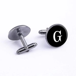 Macro shot of gun-black letter G cufflinks with polished finish and T-bar closures