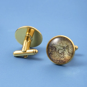 Macro shot of gold cufflinks with vintage world map design and glass dome over blue background
