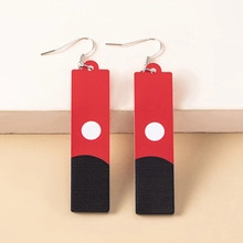 Detail of red and black anime earrings with white circle pattern on flat lay background