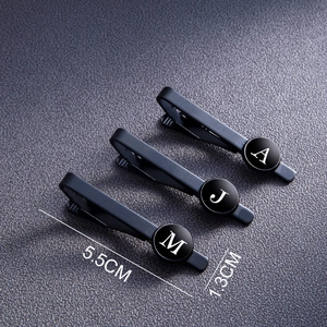 Matte black stainless steel men's letter tie clips with round initials on leather texture