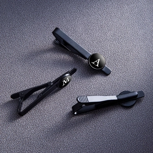 Matte black metal tie clip set with white letter A and M on round glass gems