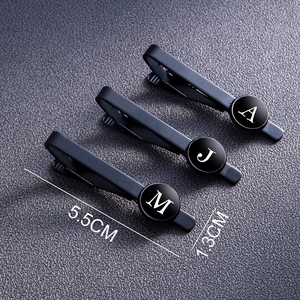 Detail of matte black tie clips showing 5.5cm length and circular alphabet initials
