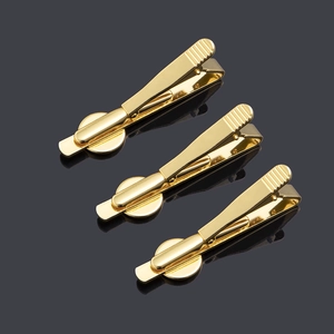 Detailed view of polished gold metal tie clips with non-slip texture and glossy finish
