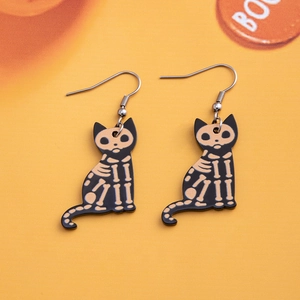 Macro detail of acrylic black cat skeleton earrings with metallic hooks on orange background