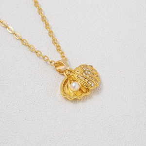 Detail of rose gold scallop pendant featuring encrusted crystals and a central white pearl