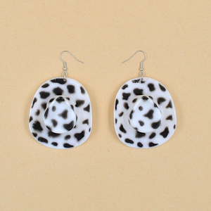 Detailed view of western cowboy hat earrings with black and white cow print textures