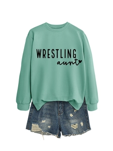 Flat lay of a mint green crewneck sweatshirt with Wrestling Aunt print and denim shorts