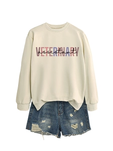 Dettaglio della felpa beige Veterinary Assistant e pantaloncini denim strappati