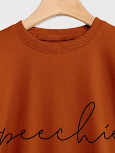 Close-up of ribbed crewneck and speechie script print on terracotta sweatshirt