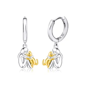 Detailed view of silver hoop earrings featuring a girl hugging a gold-plated cat pendant