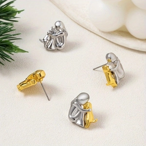 Polished silver and gold girl hugging dachshund stud earrings on a textured surface