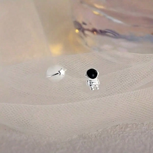 Pendientes asimétricos de astronauta y planeta ojo de gato sobre fondo de encaje plata