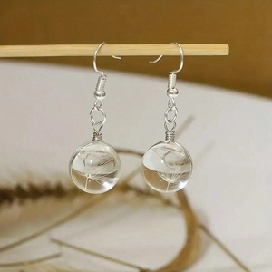 Detail of handmade glass globe earrings featuring real dandelion seeds inside