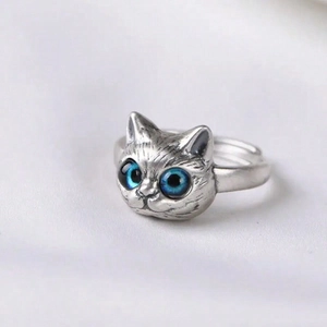 Detail of vintage silver cat head ring with blue gemstone eyes and textured fur engraving