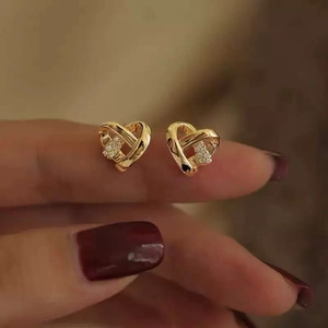 Elegant gold heart earrings with crystal rhinestones shown on model with red nails