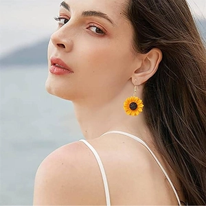 Gros plan de boucles d'oreilles tournesol avec pétales jaunes portées par un mannequin
