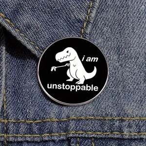 Dettaglio macro della spilla in smalto con dinosauro e scritta 'i am unstoppable'