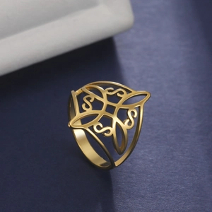 Polished golden stainless steel ring with Celtic knot cutouts on textured background