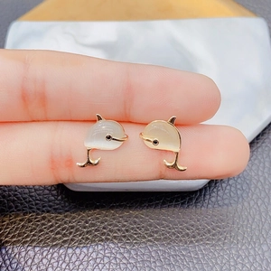 Dolphin earrings in gold plating with white cat eye stone held for size reference