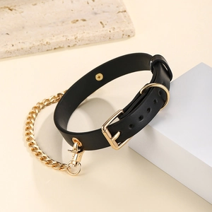Verstelbare zwarte lederen hondenhalsband met gouden schakelketting op beige achtergrond