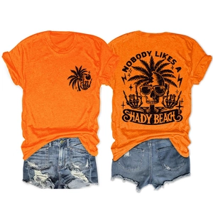 Flat lay of an orange t-shirt with a skeleton palm tree beach print and denim shorts