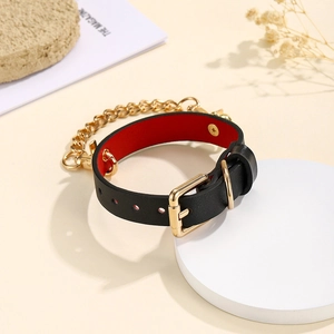 Bracelet punk en cuir noir avec chaîne dorée et doublure rouge sur support d'exposition