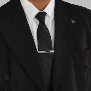 Close-up of business tie clip with inlaid diamonds and black enamel on navy tie