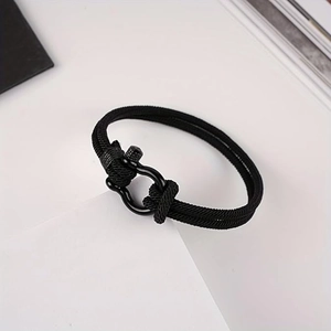 Detail of black double-braided cord bracelet with matte black metal horseshoe buckle
