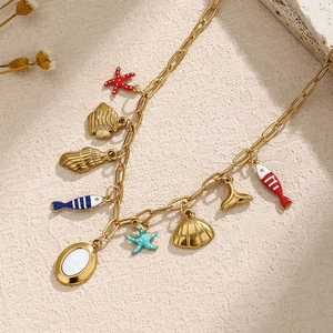 Gold ocean themed necklace with seashell, starfish and fish charms on a rustic background