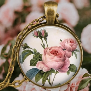 Gros plan du collier vintage en bronze avec motif de rose rose et fond floral