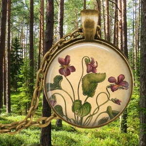 Détail d'un collier pendentif vintage rond avec une illustration de fleur de violette