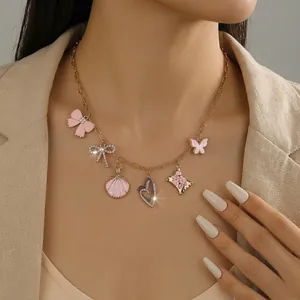Detail shot of ocean-style gold necklace with pink enamel shells and bow on female neck