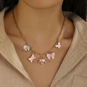 Close-up of gold multi-pendant necklace with pink enamel charms on model neck