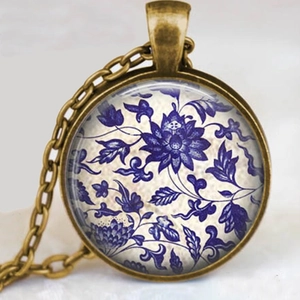 Détail macro du collier en bronze antique avec motif floral bleu sous dôme de verre