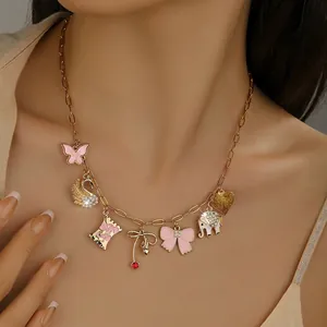 Close-up of golden necklace with pink enamel butterfly, elephant, and sweet candy pendants