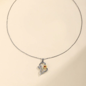Macro shot of silver heart pendant with engraved you are my sunshine and red sunflower