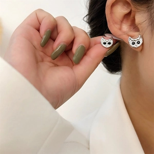 Close-up of owl stud earrings with black gemstone eyes worn on the earlobe