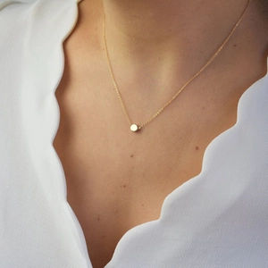 Close-up of a minimalist golden stainless steel necklace with small round bead pendant