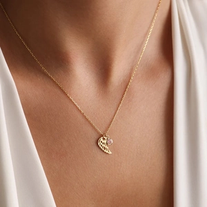 Collar de alas de ángel doradas con pequeña piedra rosa en una fina cadena de mujer