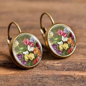 Macro detail of bronze leverback earrings featuring vintage floral patterns under glass