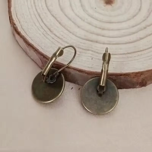 Vintage bronze rose lever-back earrings displayed on a natural wood ring background