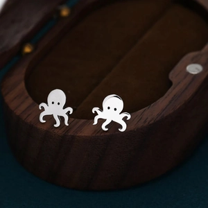 Detailed macro view of cute octopus shaped stainless steel stud earrings on a wood box