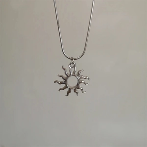 Détail du pendentif soleil évidé sur une chaîne serpent argentée élégante et fine